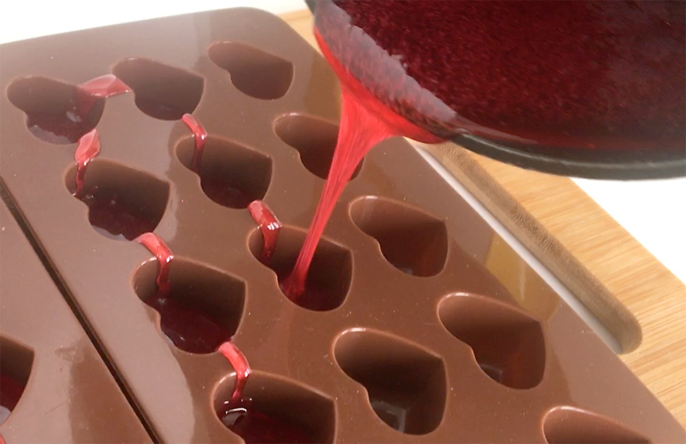 Pouring melted candy from a pot into heart molds