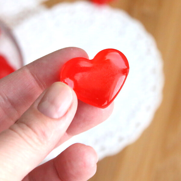 Hand holding a red cinnamon heart hard candy
