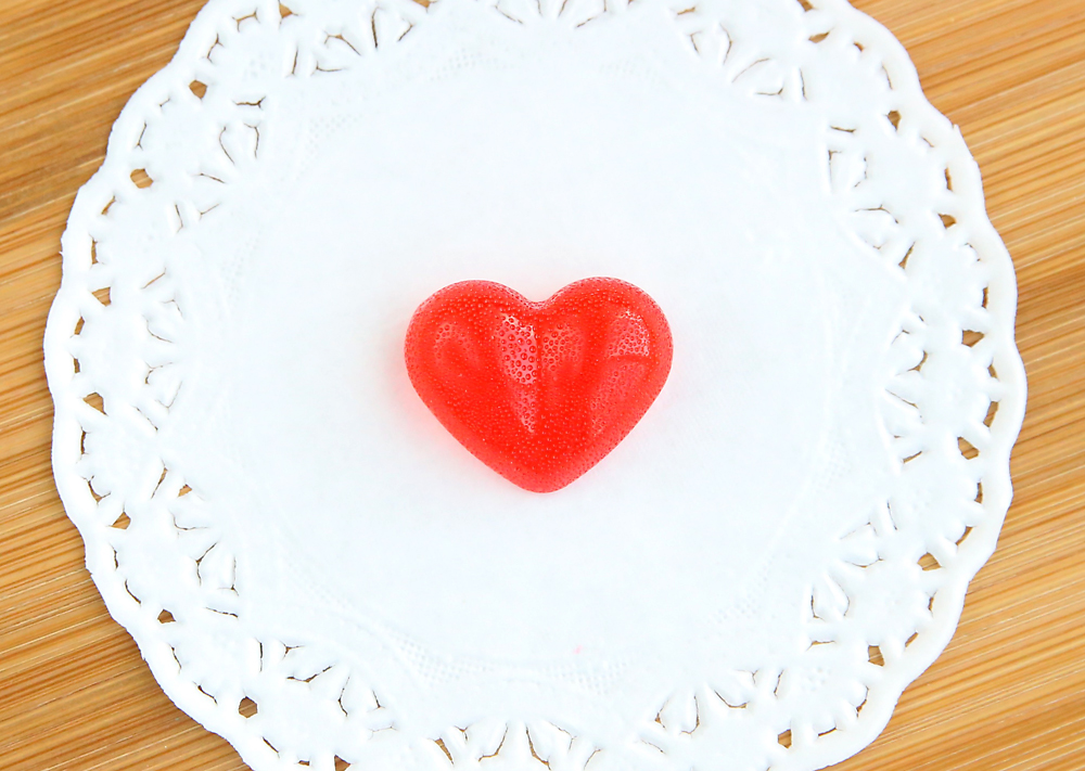 A red cinnamon heart candy on a paper doily