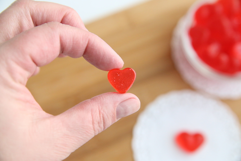 Hand holding a tiny cinnamon heart hard candy