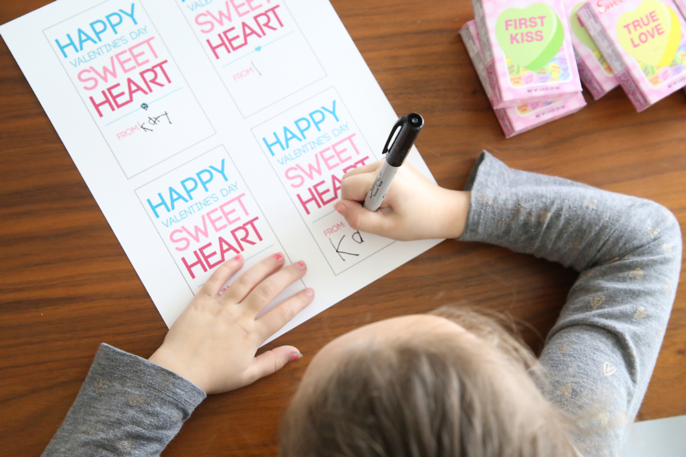 Little girl signing her name of valentines