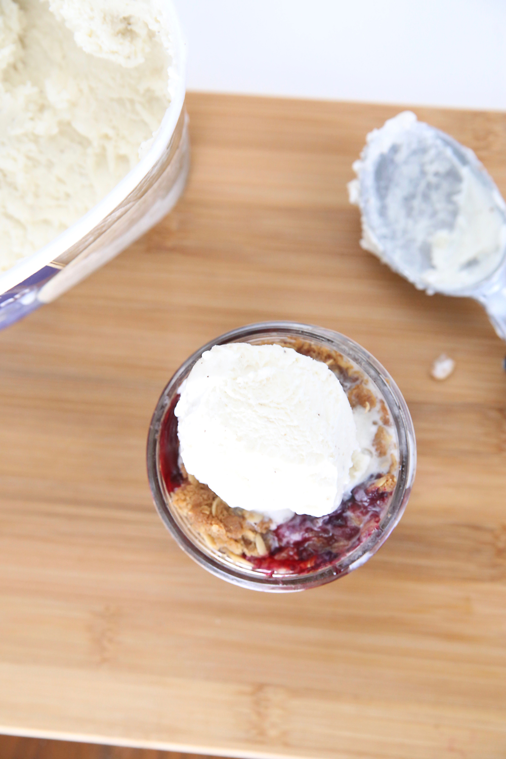 Mini berry crisp in a small mason jar with scoop of vanilla ice cream on top