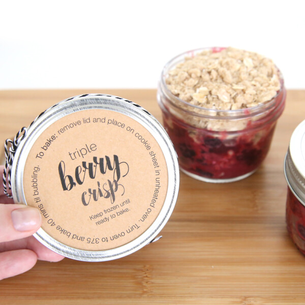 hand holding a mini triple berry crisp in a small mason jar