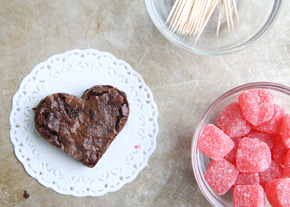 a heart brownie on a doily, with toothpicks and jelly heart candies