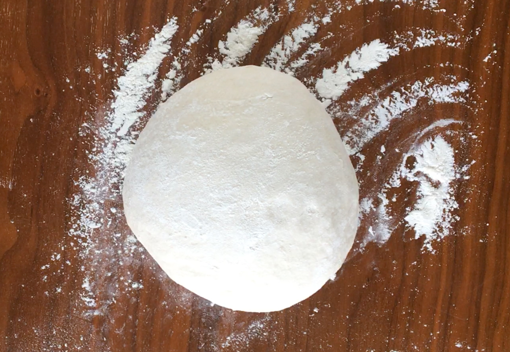 Bread dough formed into a ball on a floured table