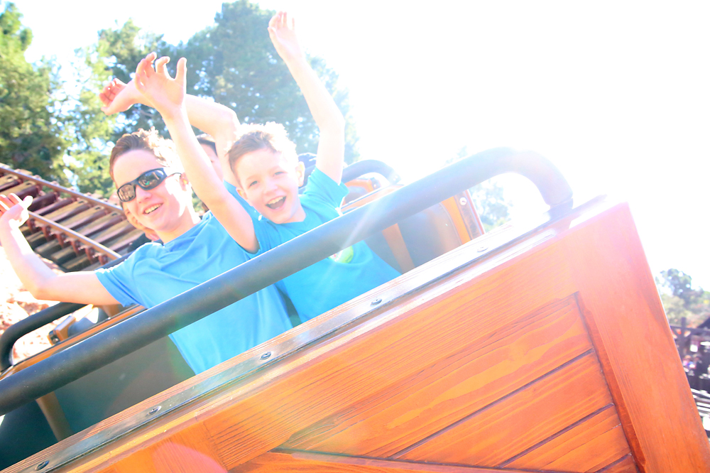 Boys with their arms up riding a roller coaster