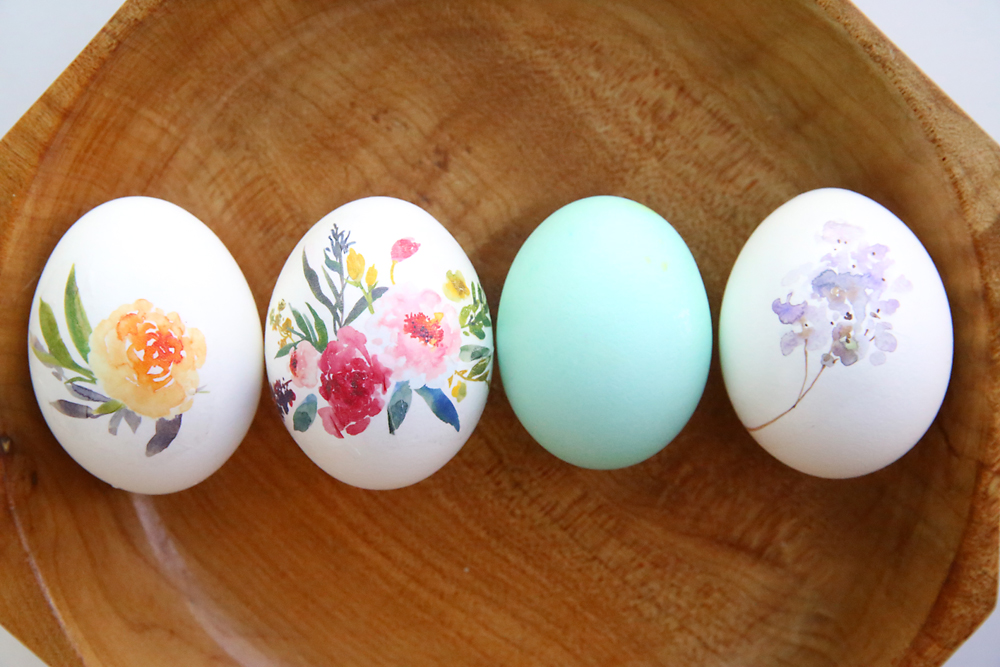 Eggs decorated with flowers lined up on a wooden plate