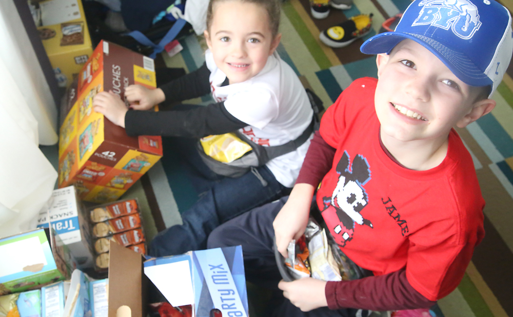 Kids opening boxes of snack packs to fill up their fanny packs with