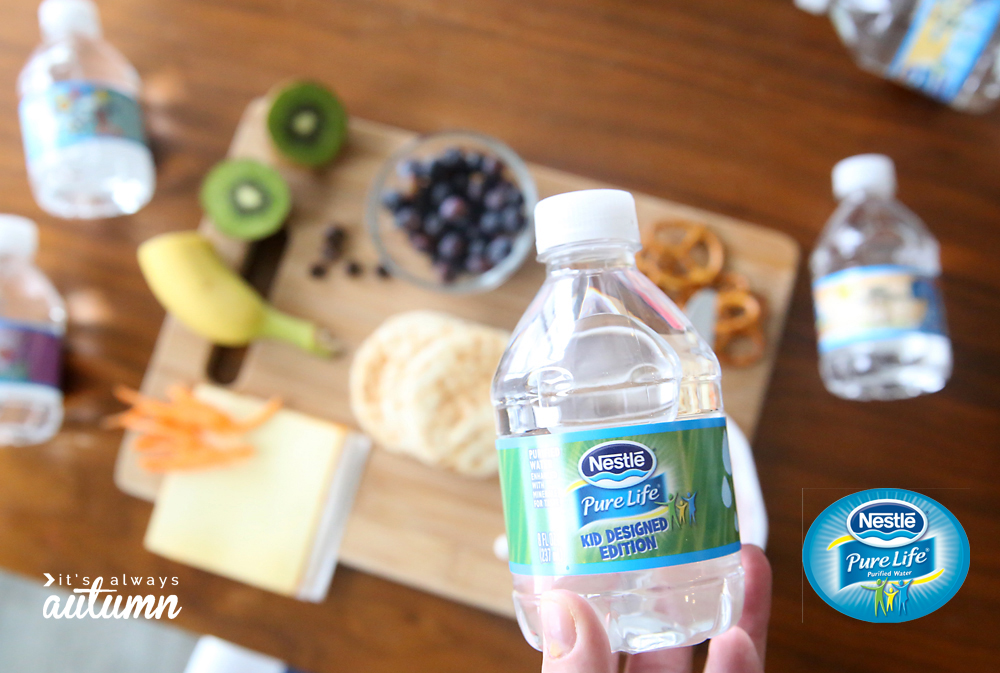 Hand holding small water bottle near snack ingredients