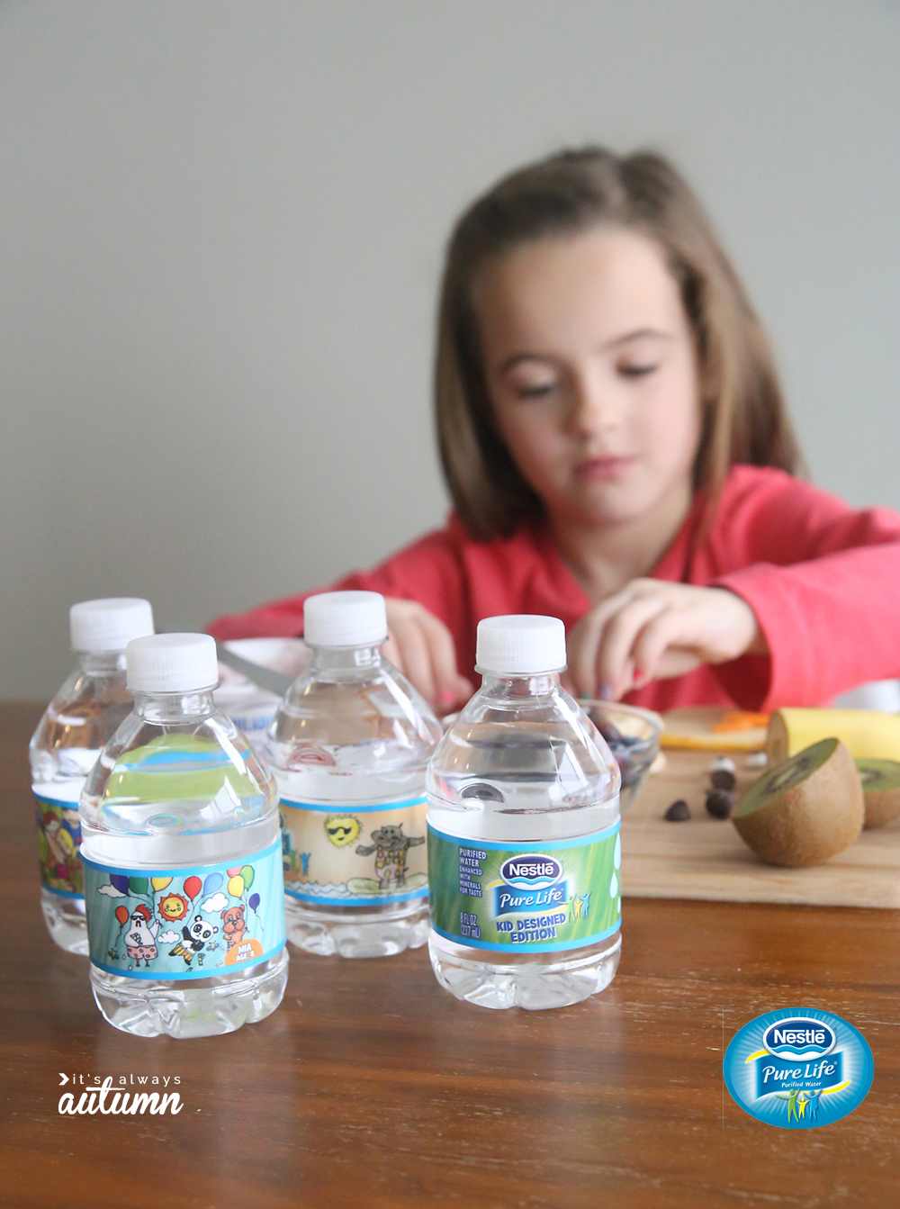 A little girl sitting at a table with water bottles