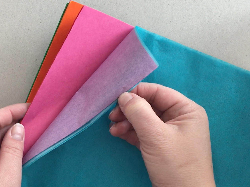 Hands holding various colors of tissue paper