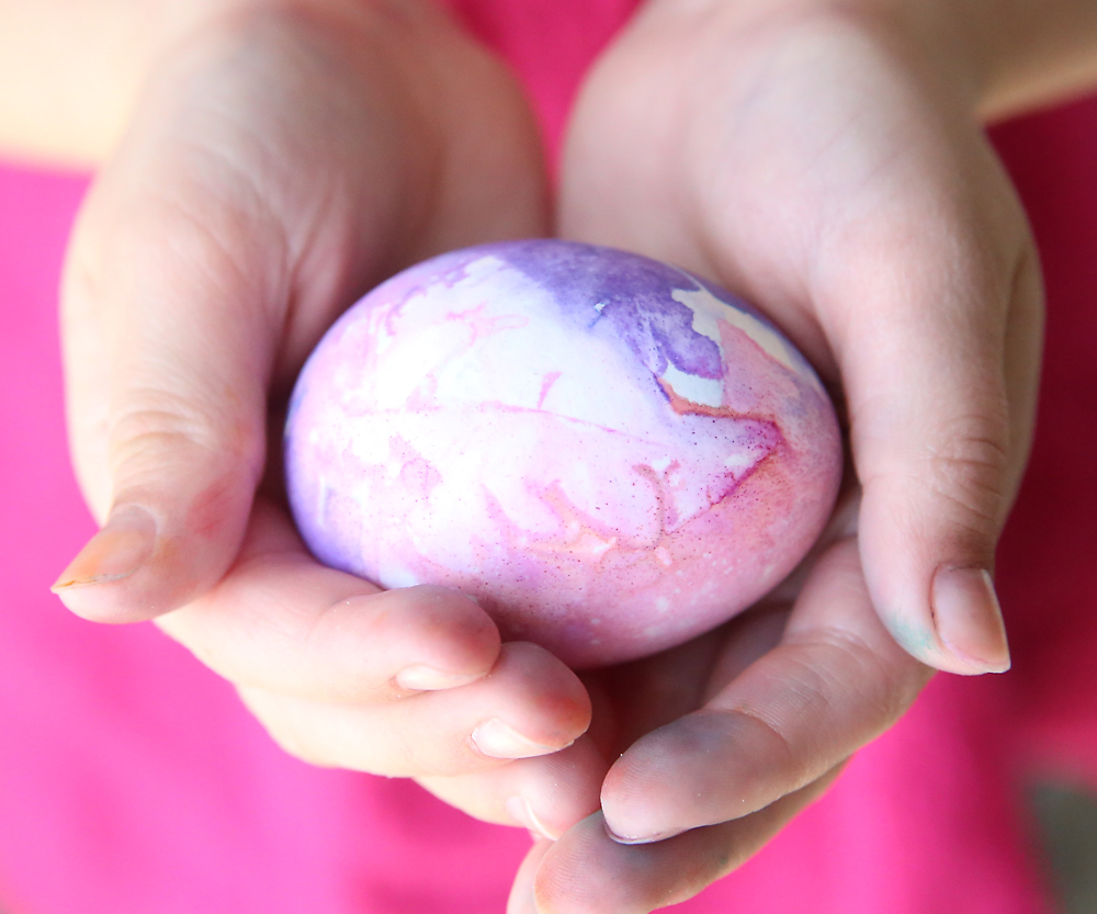 Hands holding a pink and purple Easter egg