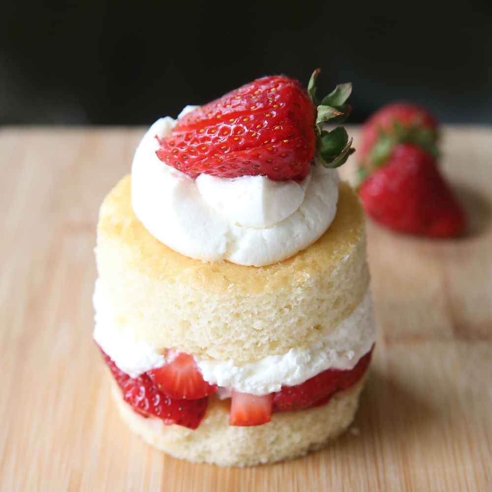 Round piece of strawberry shortcake on a wood cutting board