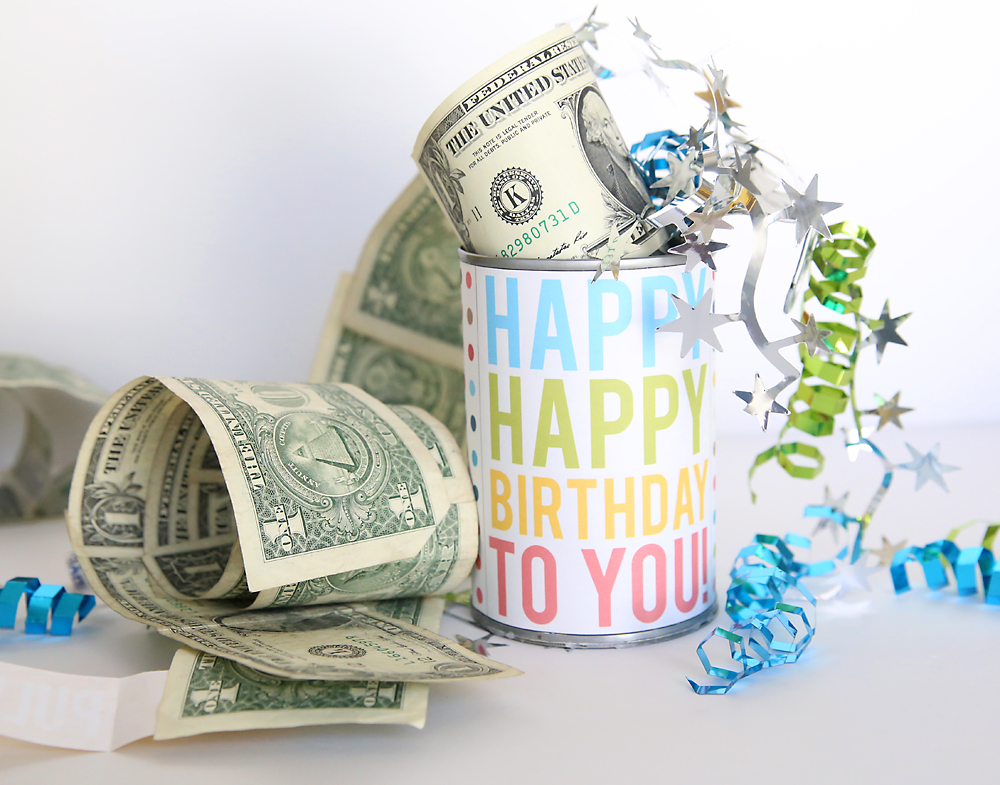 Happy happy birthday sign on a poptop can that\'s been opened to show a roll of one dollar bills