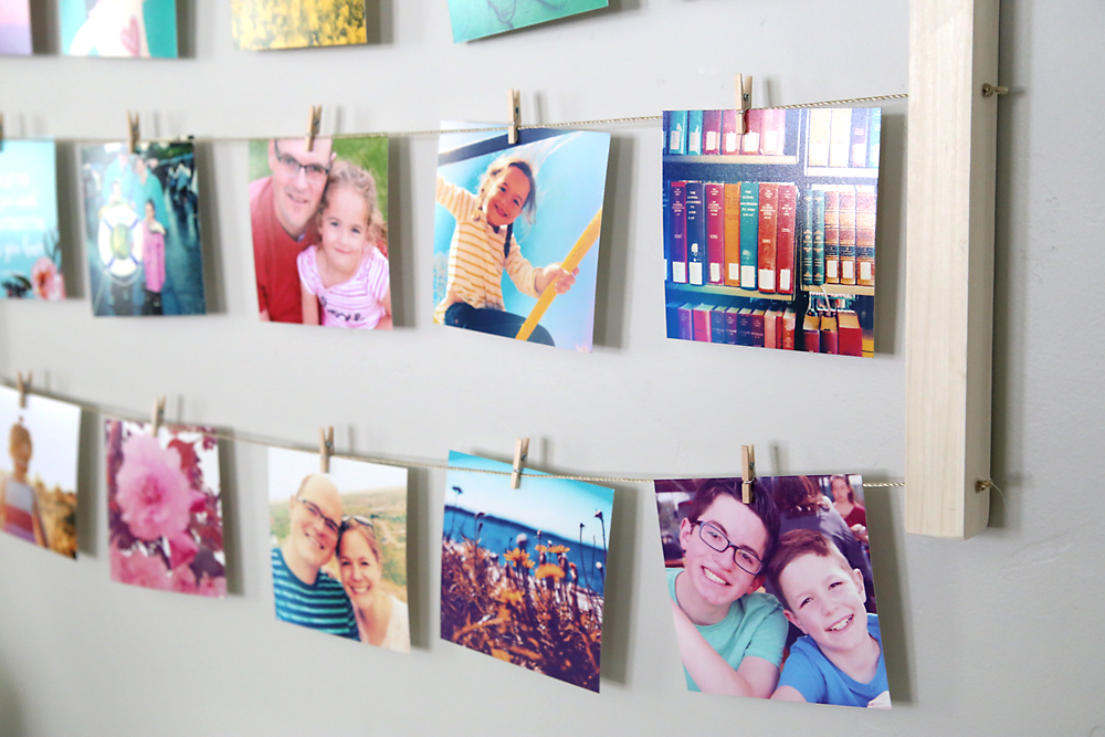 Photos hanging on lines of twine with small clothespins