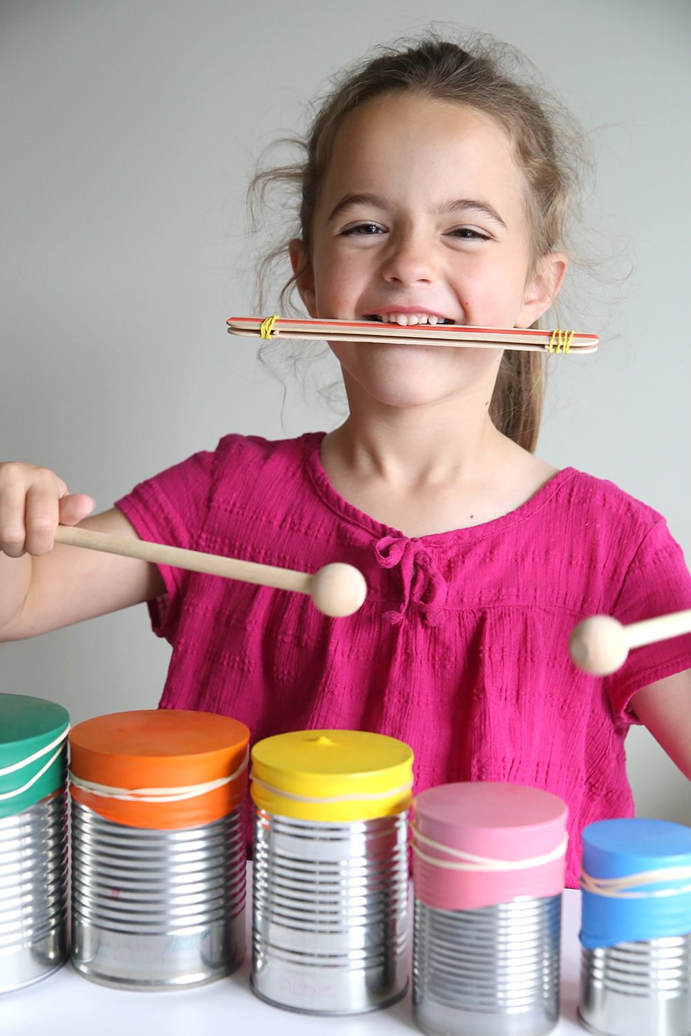 Girl playing DIY drumset and kazoo