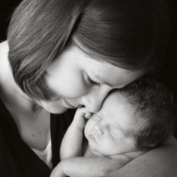 Black and white photo of mother snuggling her baby