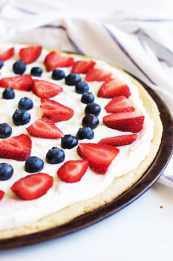 Cookie pizza topped with cream and red and blue berries