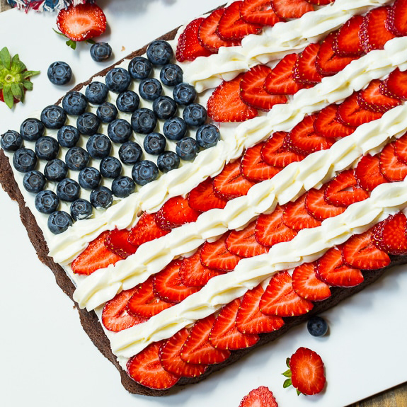 Brownies covered with frosting, strawberries and blueberries to look like an American flag