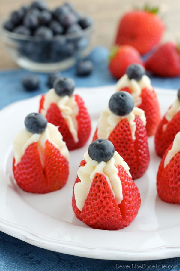 Strawberries sliced open and filled with cream, topped with a blueberry