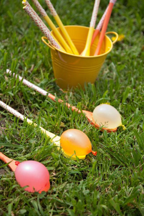Filled water balloons on wood spoons on the grass