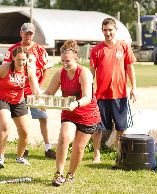 Summer water game: a group of people running while holding a tray of cups filled with water