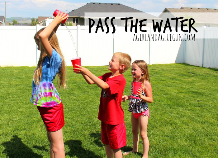 Children standing in a row pass water over their heads from cup to cup - summer water games