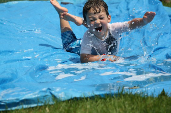 A young boy sliding down a large DIY slip and slide