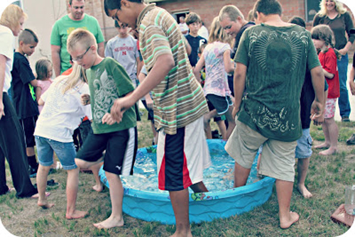 A group of people standing with one foot in a wading pool
