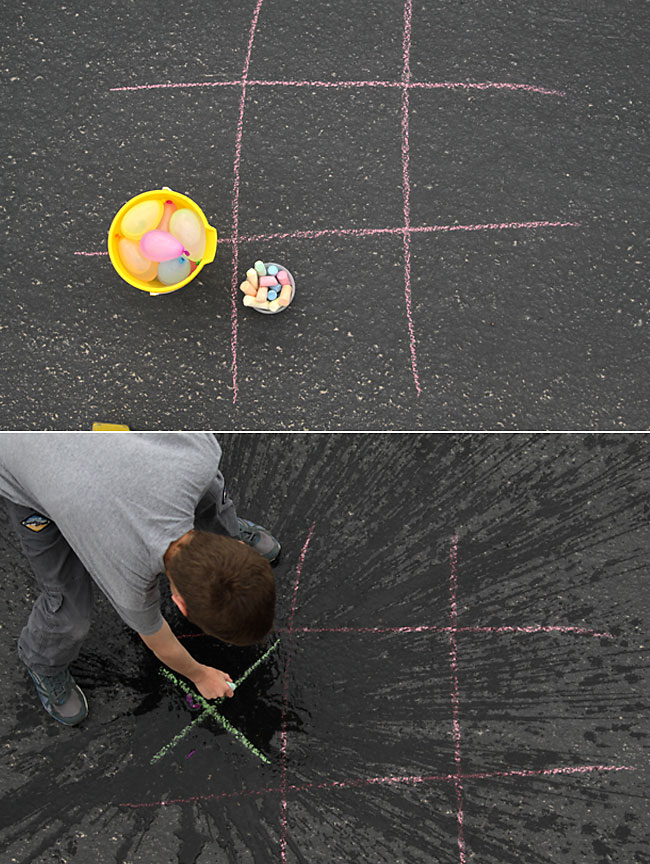 A tic tac toe drawing in chalk on the sidewalk and water balloons