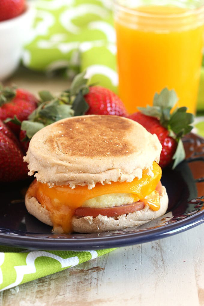 Egg muffin breakfast sandwich on a plate with strawberries