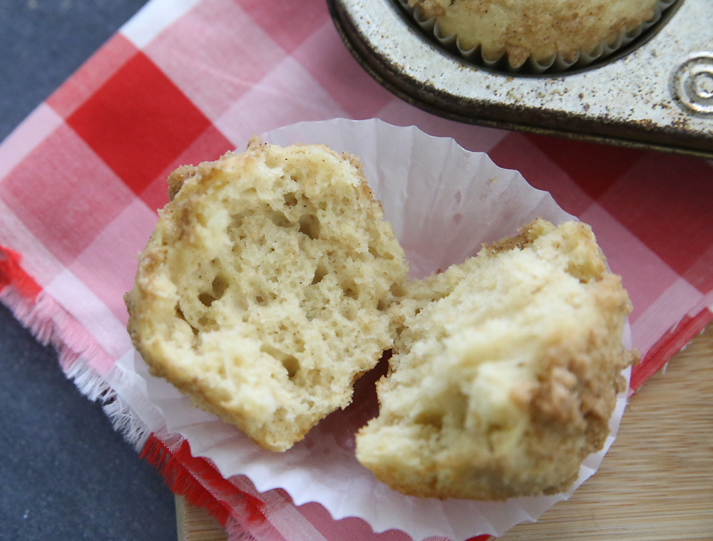 An instant oatmeal muffin broken in half on a red gingham tablecloth