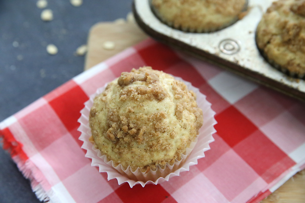 A streusel topped muffin on a gingham tablecloth