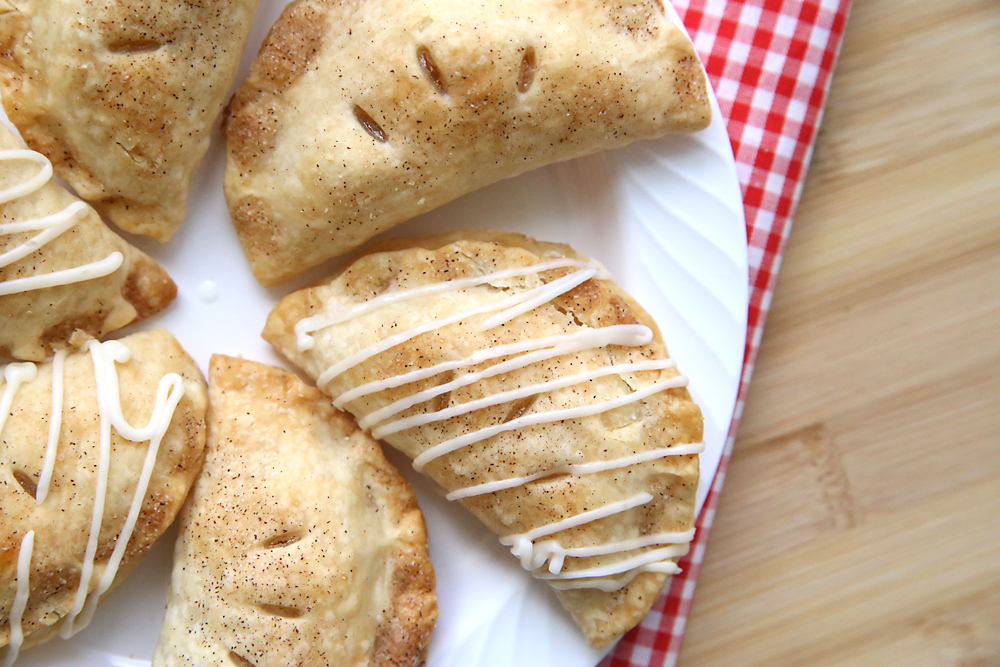 Mini apple hand pies on a plate, some with glaze