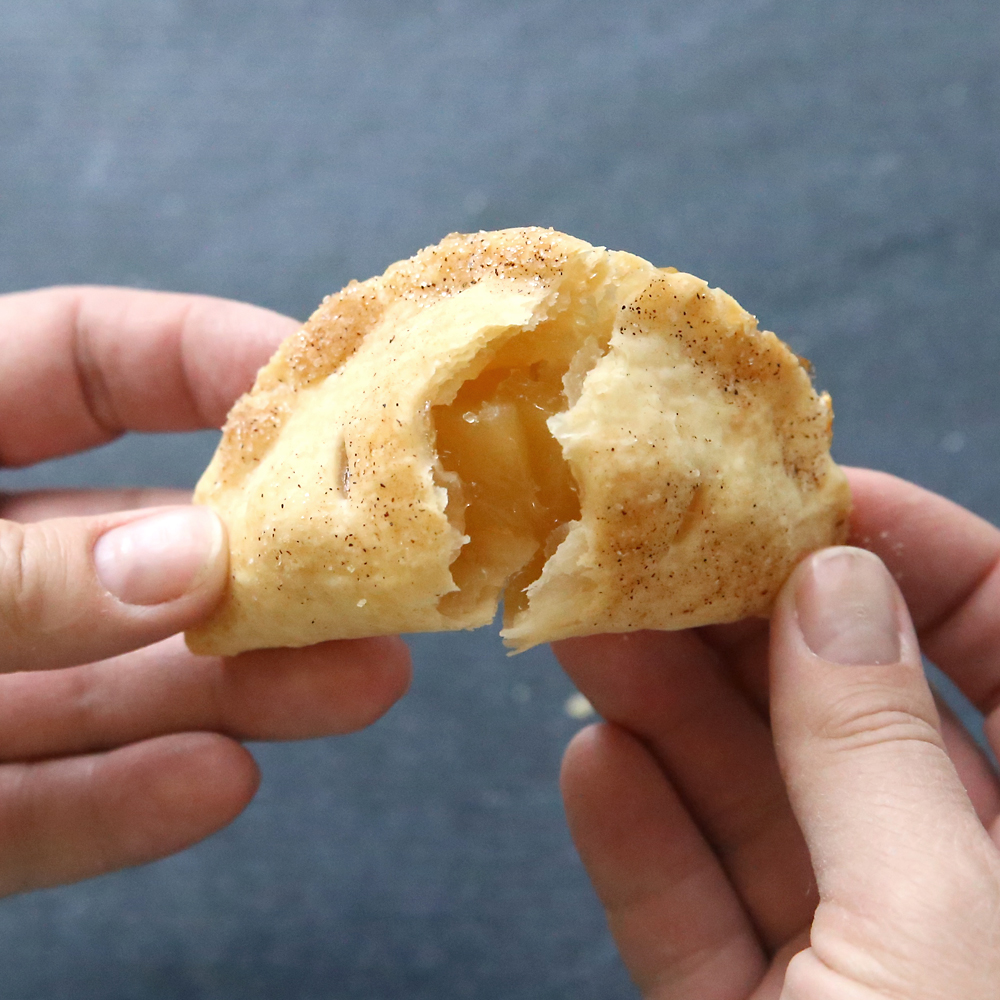 Hands breaking open an apple hand pie