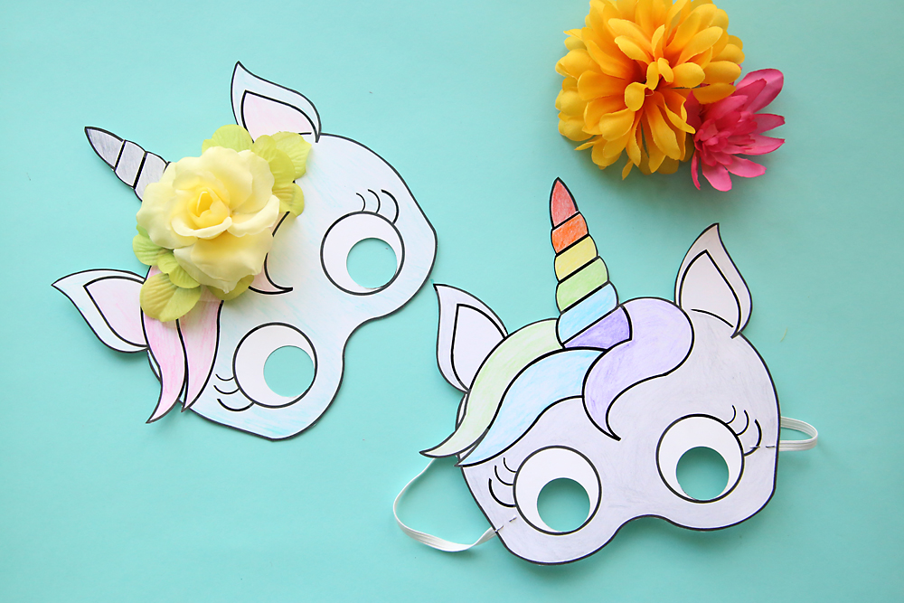 Paper unicorn masks that have been colored, with fake flowers