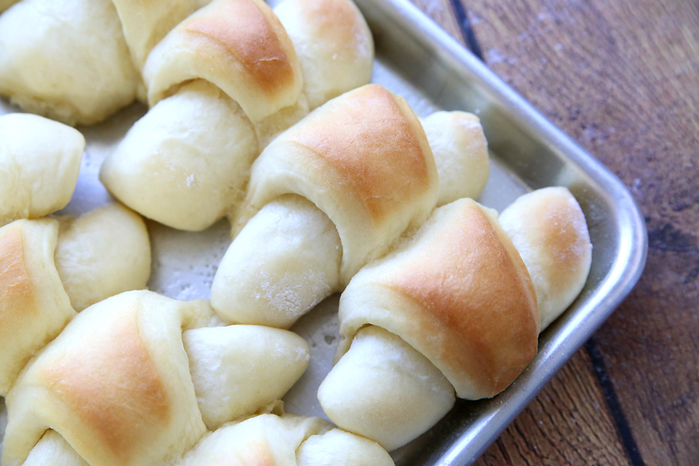 A closeup of homemade crescent rolls on a baking sheet