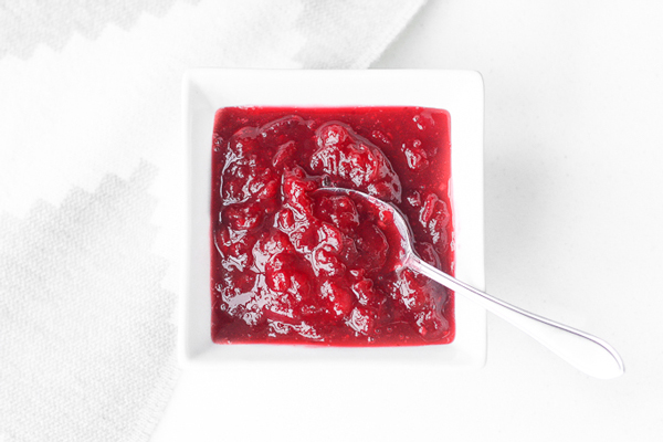 Bright red homemade cranberry relish in a square white bowl (make ahead Thanksgiving side dish)