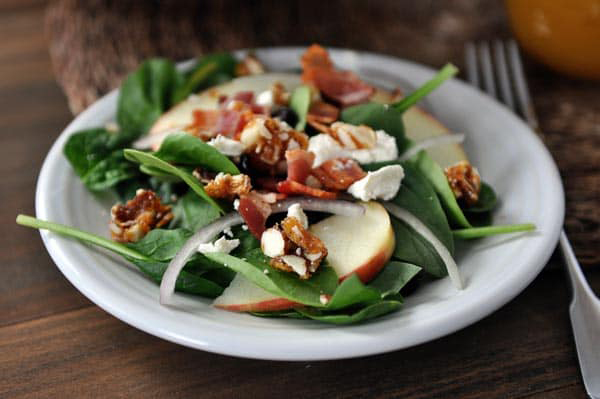 Spinach bacon salad on a plate, with onions and apples