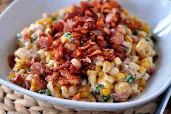 A bowl of corn salad topped with bacon