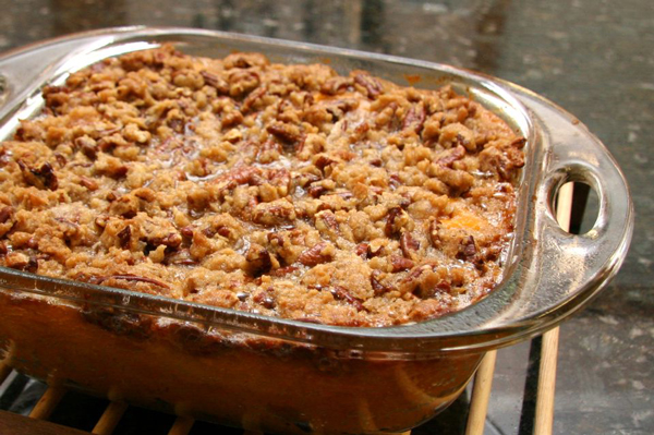 Baked casserole dish of Thanksgiving sweet potatoes with pecans on top