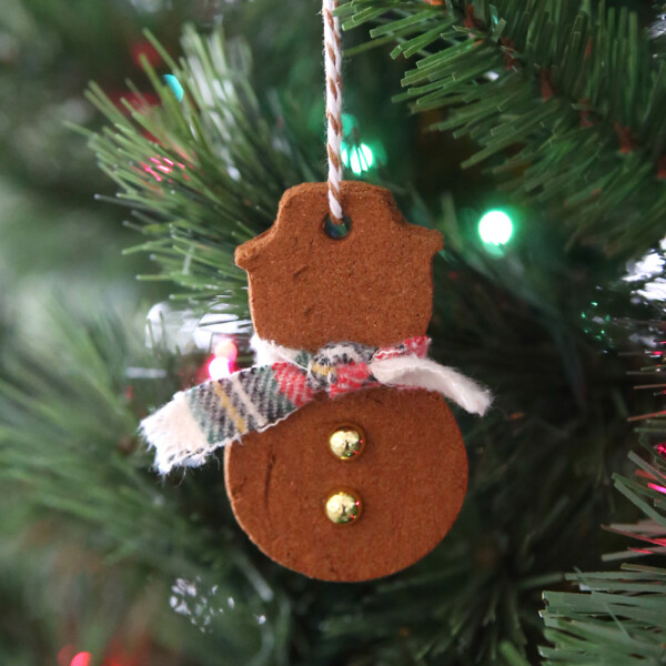 Cinnamon ornament in the shape of a snowman hanging on a Christmas tree