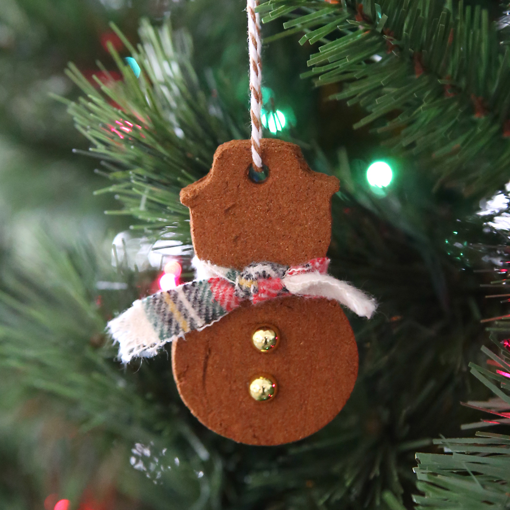 Cinnamon ornament in the shape of a snowman hanging on a Christmas tree