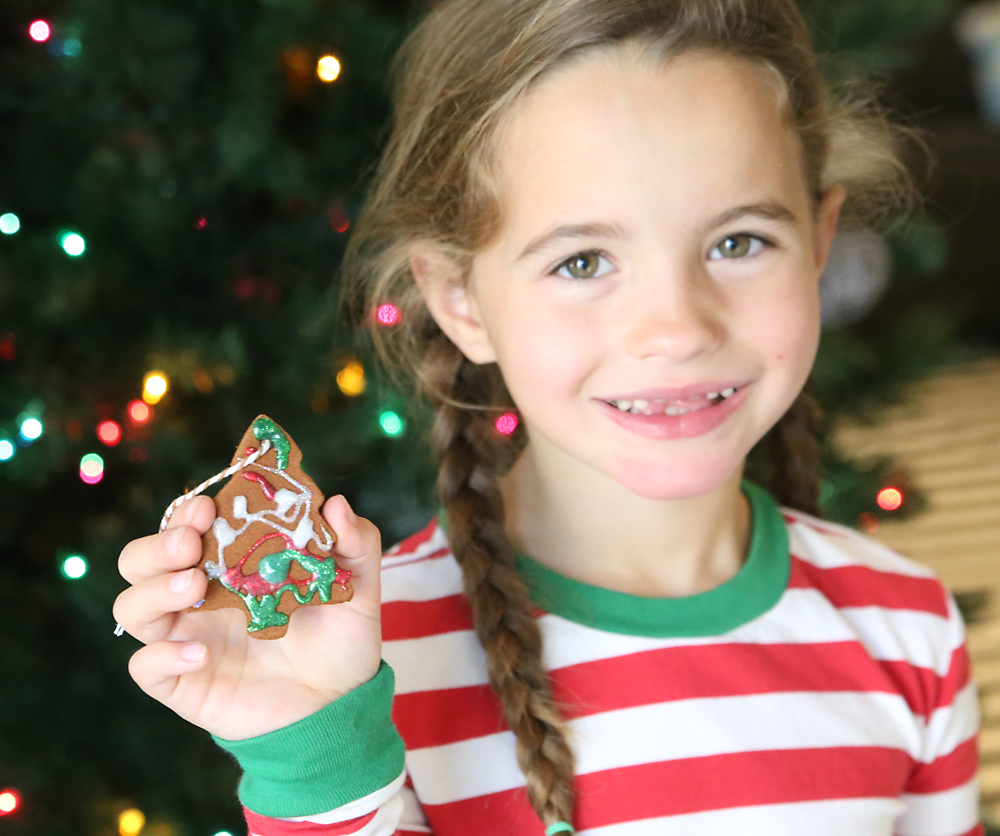 Girl with homemade cinnamon ornament decorated with glitter glue.