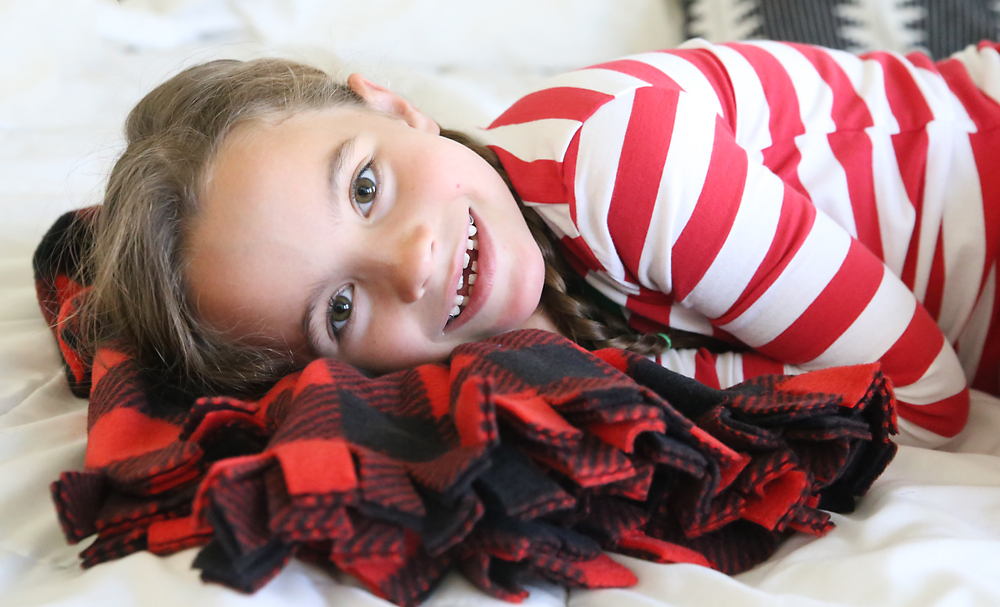 A girl snuggle with a fringed fleece blanket