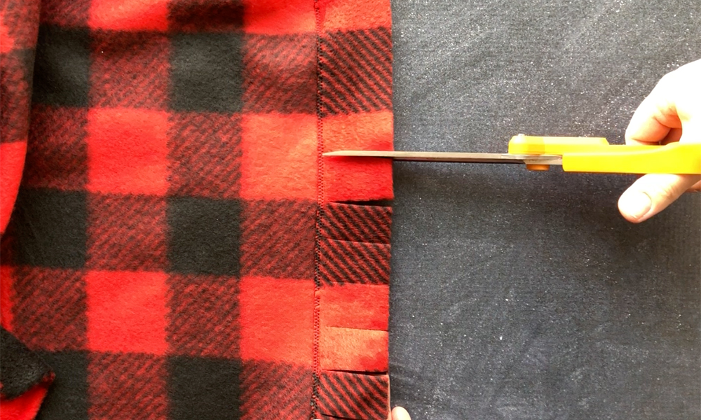 Cutting fringe into the edge of the fleece blanket