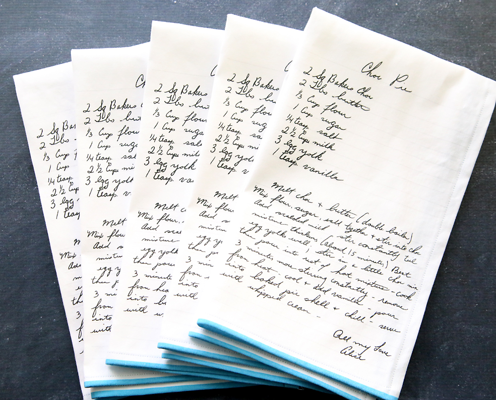 Stack of kitchen towels which have all had a handwritten recipe printed on them