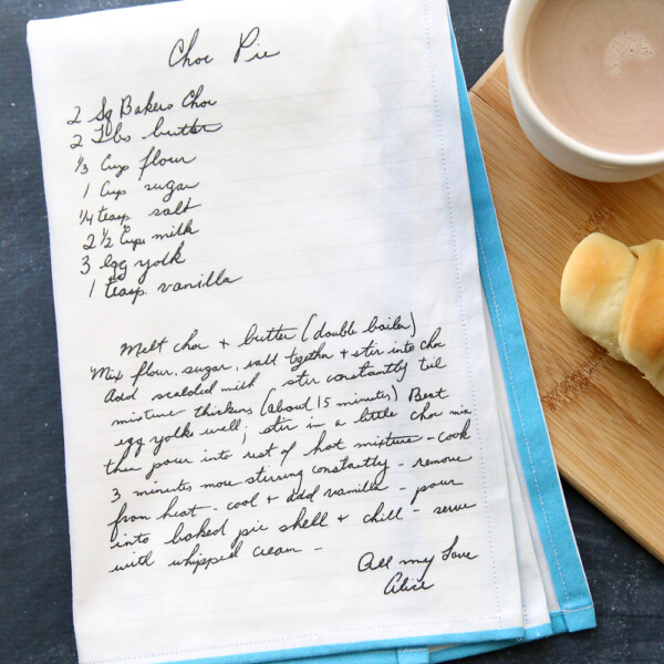 Kitchen tea towel with recipe printed on it, next to a cup of cocoa