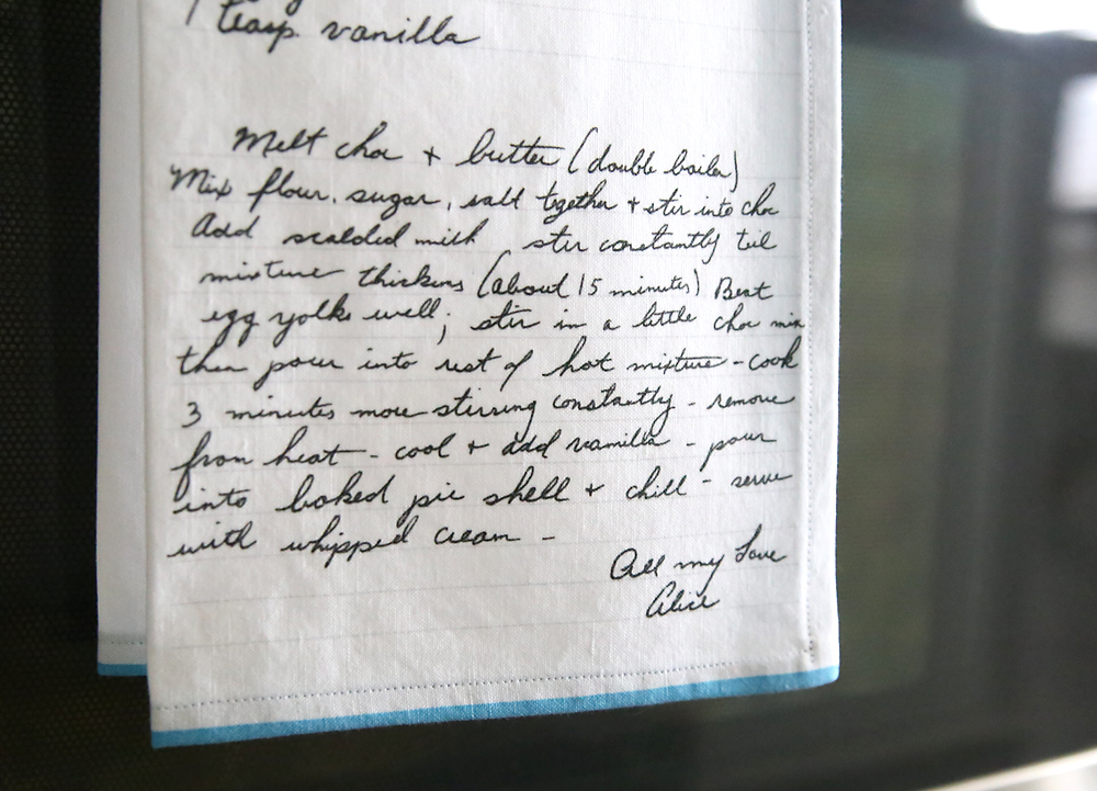 Kitchen towel with handwritten recipe on it hanging on an oven door