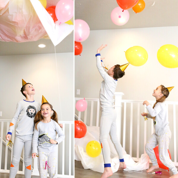 Children wearing New Year's Eve party hats playing with balloons dropping from the ceiling